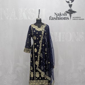 May include: A dark navy blue salwar kameez set featuring intricate gold embroidery and sequin embellishments on the tunic and matching wide-leg trousers. The ensemble includes a sheer navy blue dupatta with a decorative gold border and floral motifs.
