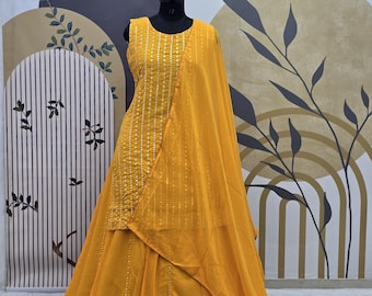Può includere: Un abito giallo senza maniche con un dupatta abbinato. L'abito ha una gonna a pieghe e un corpetto con scollo rotondo. L'abito è decorato con piccole paillettes argentate.