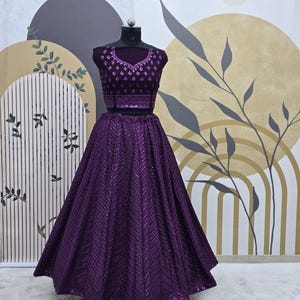 Puede incluir: Un conjunto de top y falda de lentejuelas morado. La falda es una falda circular completa con un patr&oacute;n de chevron. El top tiene un escote redondo y est&aacute; decorado con lentejuelas.