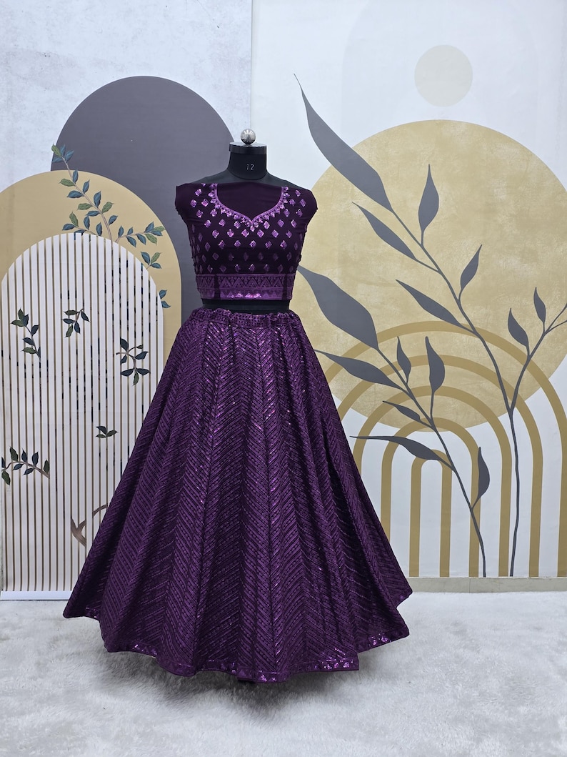 Puede incluir: Un conjunto de top y falda de lentejuelas morado. La falda es una falda circular completa con un patr&oacute;n de chevron. El top tiene un escote redondo y est&aacute; decorado con lentejuelas.