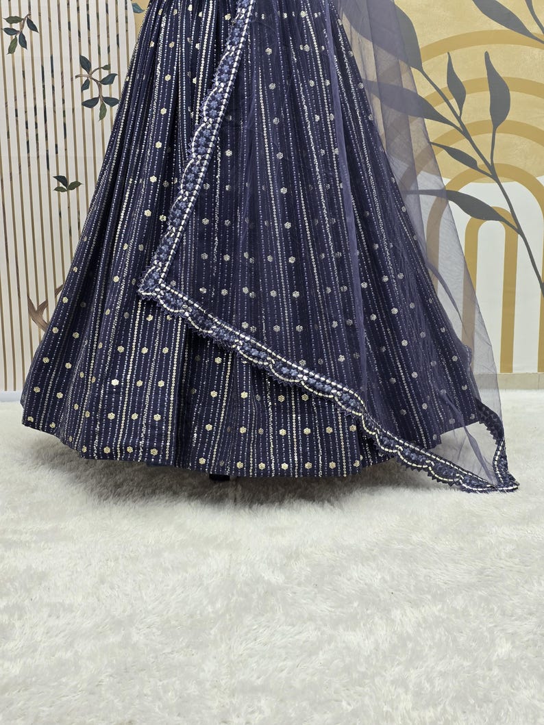 May include: A navy blue formal dress with silver dot and stripe embellishments. The dress features a flowing skirt and a matching sheer shawl with a scalloped edge. The fabric has a subtle sheen, and the design is elegant.