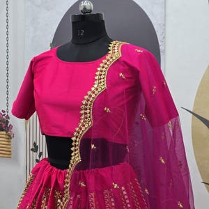 Pode incluir: Um lehenga bordado em rosa e dourado com um choli e um dupatta combinando. O lehenga tem uma saia rodada com bordados intrincados e uma borda dourada. O choli &eacute; um top curto sem mangas com um design de bordado semelhante. O dupatta &eacute; um tecido transparente com uma borda dourada.