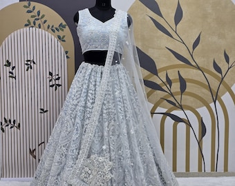 May include: A light blue embroidered lehenga with a matching sleeveless blouse. The lehenga is made of net fabric and features intricate silver embroidery. The outfit is perfect for a special occasion.