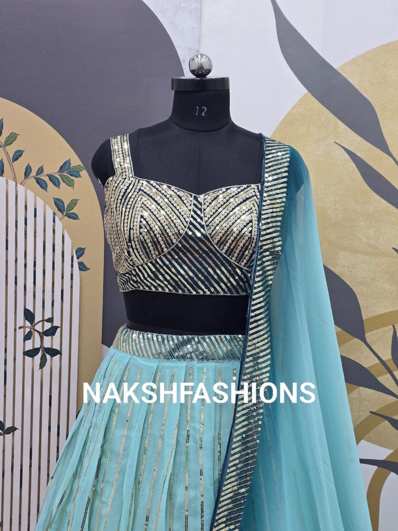 Op de afbeelding: Een turquoise blauwe en zwarte crop top en rok set met gouden pailletten. De top heeft een sweetheart halslijn en de rok is A-lijn. De set is op een mannequin en de tekst "NAKSHFASHIONS" is zichtbaar.