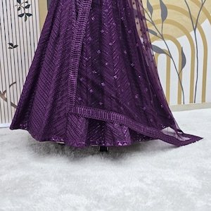 Puede incluir: Una falda de lentejuelas morada con una superposici&oacute;n transparente a juego. La falda tiene un patr&oacute;n de chevron y est&aacute; decorada con peque&ntilde;as lentejuelas.