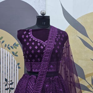 Puede incluir: Un lehenga bordado de color morado con un choli y un dupatta a juego. El lehenga presenta un patr&oacute;n geom&eacute;trico y lentejuelas. El choli tiene un escote en V y tambi&eacute;n est&aacute; adornado con lentejuelas.