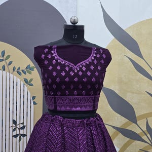 Puede incluir: Un conjunto de top corto y falda morado con un patr&oacute;n geom&eacute;trico y lentejuelas. El top tiene un escote redondo y es sin mangas. La falda es una falda de c&iacute;rculo completo.