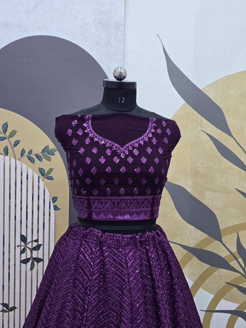 Puede incluir: Un conjunto de top corto y falda morado con un patr&oacute;n geom&eacute;trico y lentejuelas. El top tiene un escote redondo y es sin mangas. La falda es una falda de c&iacute;rculo completo.