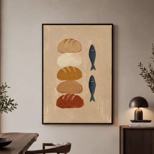 May include: A framed wall art print on a beige background featuring a vertical stack of five rounded bread loaves in varying shades of brown, tan, and cream, positioned next to two dark blue fish illustrations arranged vertically.