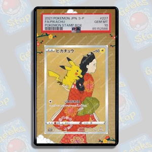 May include: A Pokemon trading card featuring Pikachu and a woman in a red and white kimono. The card is from the 2021 Pokemon Japanese Stamp Box set and is graded GEM MT 10. The card is titled "Pikachu" and has a Japanese description. The card is in a protective case.