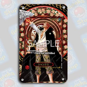 Puede incluir: Una tarjeta coleccionable con una ilustración de personaje, enmarcada en un borde decorativo rojo y dorado con detalles florales. El personaje tiene el pelo rojo y una capa negra. La tarjeta incluye el texto "SAMPLE" y "Card not included".