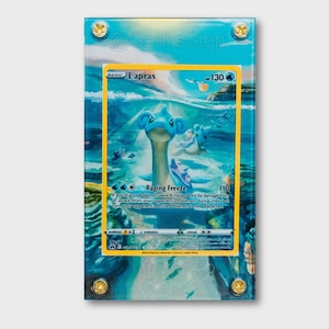 May include: A rectangular acrylic display case containing a Lapras Pokemon trading card. The card features a blue aquatic creature in an ocean scene with the text Lapras, 130 HP, and Raging Freeze. The case is secured by four gold-colored screws.