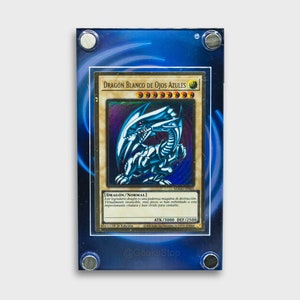 Puede incluir: Una carta de comercio azul y dorada con un dragón blanco de ojos azules. La carta se titula "Dragón Blanco de Ojos Azules" y tiene el texto "[DRAGON/NORMAL] Este legendario dragón es una poderosa máquina de destrucción, Virtualmente invencible, muy pocos se han enfrentado a esta impresionante criatura y han vivido para contarlo." La carta tiene un poder de ataque de 3000 y un poder de defensa de 2500.