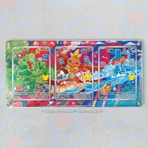 May include: A rectangular metal display frame featuring three slots for trading cards. The design showcases colorful illustrations of Treecko, Torchic, and Mudkip with various icons. The text "Cards not included - Hand-made art" is printed at the bottom.