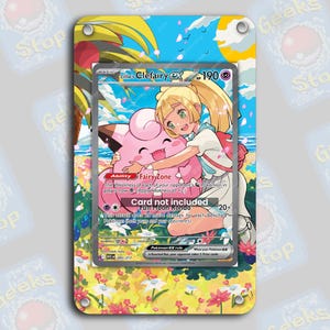 May include: A protective case featuring a Pokémon trading card. The card depicts Lillie's Clefairy EX with a girl hugging a pink Clefairy. The case has a floral and palm tree background. The text "Card not included" is visible.