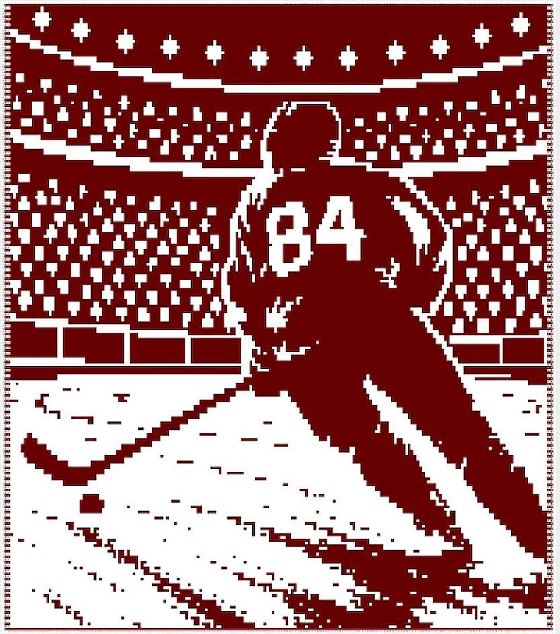 May include: A maroon and white woven blanket featuring a pixelated graphic of a hockey player wearing a jersey with the number 84. The player is shown on the ice with a hockey stick and puck, set against a stadium background with a crowd.
