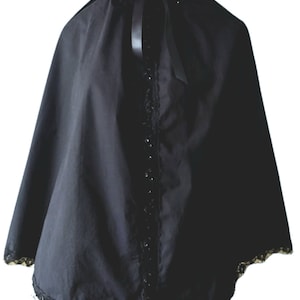 May include: A black cape with a lace trim and a black satin ribbon tied at the neck. The cape has a high collar and is made of a soft, flowing fabric.
