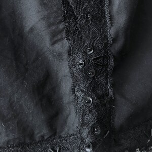 May include: Black skirt with a lace trim and sequins. The lace trim is on the side of the skirt and the sequins are scattered throughout the lace.