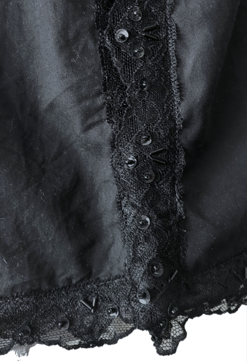 May include: Black skirt with a lace trim and sequins. The lace trim is on the side of the skirt and the sequins are scattered throughout the lace.