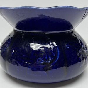 May include: A cobalt blue ceramic planter with a scalloped rim and embossed floral design.