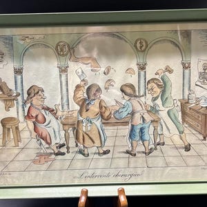 May include: A vintage framed illustration depicting a humorous scene of four men performing a surgical procedure in a medieval setting. The illustration is titled "L'intervento chirurgico" and features a detailed background with architectural elements and a skull and crossbones symbol.