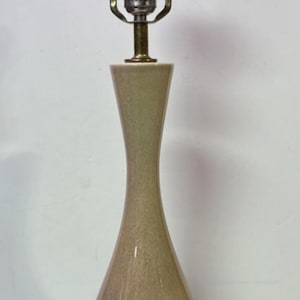 May include: A vintage table lamp with a two-tone brown and tan ceramic base and brass accents. The lamp has a slender, hourglass-shaped body and a brass neck supporting a light bulb. The lamp is approximately 24 inches tall.