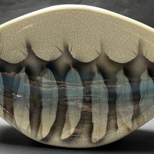 May include: A ceramic serving dish with a white crackled glaze and a design of blue and brown leaves.
