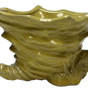 May include: A yellow ceramic planter shaped like a boot with a textured surface.