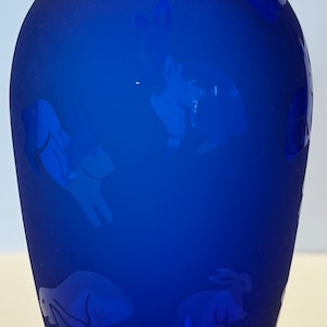 May include: A cobalt blue glass vase with a frosted finish and an etched design of rabbits and other animals.