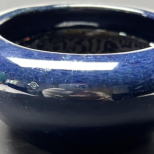 May include: A small, deep blue ceramic bowl with a glossy finish. The bowl has a rounded shape and a slightly flared rim.
