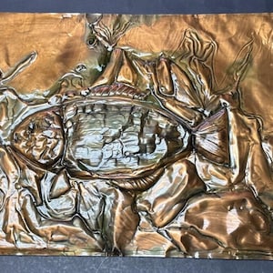 Puede incluir: Una escultura de metal de color cobre de un pez con una superficie texturizada. El pez está rodeado de formas y diseños abstractos.