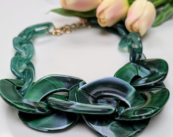 Puede incluir: Un collar verde grueso con un diseño de cadena de eslabones. Los eslabones son grandes y redondos, con un patrón de mármol.