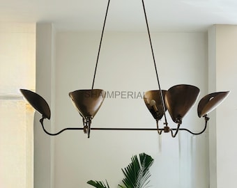 May include: A brass chandelier with five light fixtures, each with a curved, bell-shaped shade. The chandelier is hanging from a white ceiling.