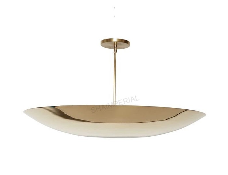 K&ouml;nnte beinhalten: Eine goldfarbene, ovale Pendelleuchte mit schlichtem, modernem Design. Die Leuchte hat eine einzelne Gl&uuml;hbirne und ein d&uuml;nnes, gerades Kabel.