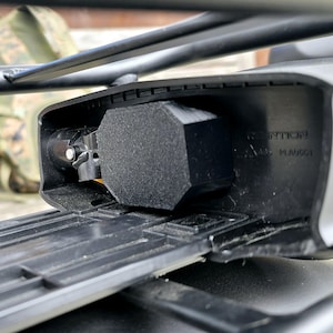 May include: Close-up of a black bike rack with a black and gray locking mechanism. The rack has a black plastic cover with the text "DIRECTION" and "4435 NUM8601" printed on it.