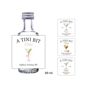 May include: A clear glass bottle with a silver cap and a label that reads "A TINI BIT Older." The label features a martini illustration and the text "Gabby's Turning 30!" Additional labels are included.
