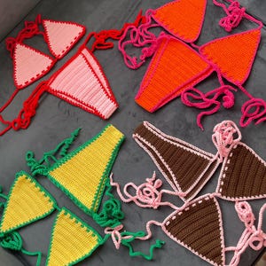 Peut inclure: Quatre ensembles de bikini crochet de différentes couleurs. Les ensembles sont faits de fil rose, orange, jaune et marron. Chaque ensemble comprend un haut triangle et un bas avec des liens.