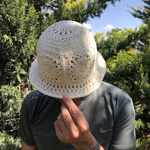 May include: A white crocheted bucket hat with a wide brim and a delicate openwork pattern.