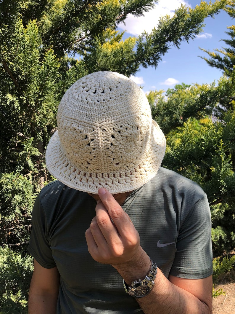 May include: A white crocheted bucket hat with a wide brim and a delicate openwork pattern.