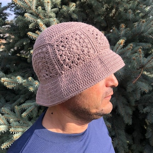 May include: A crocheted bucket hat in a light brown color. The hat has a wide brim and a textured design.