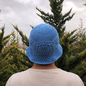 May include: A light blue crocheted bucket hat with a floral design.