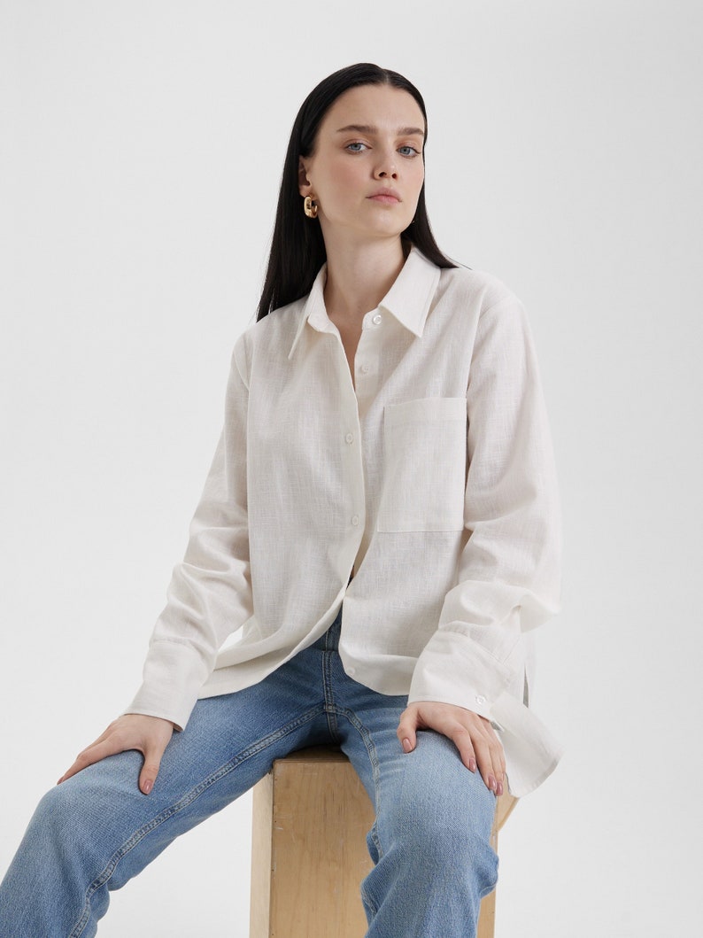 A woman sitting on a wooden block wearing a Women White Linen Oversized Shirt and jeans.