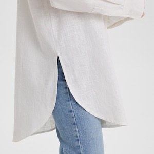 A woman wearing a Women White Linen Oversized Shirt and jeans in summer.