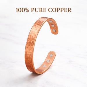 May include: A copper cuff bracelet with a hammered texture and magnetic closures. The bracelet is open-ended and features the text "100% PURE COPPER" at the top. The bracelet is a warm, reddish-brown color.