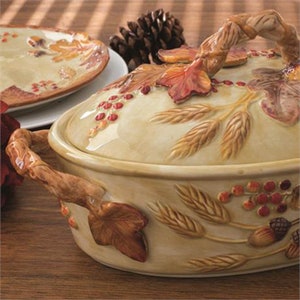 May include: A ceramic casserole dish with a lid, featuring a fall-themed design with wheat, leaves, and berries. The dish is cream-colored with brown, red, and green accents.