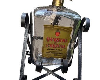 Bottiglia vintage di Amaretto di Saronno custodita in un supporto versatore basculante in ferro battuto.