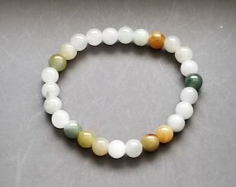 Pode incluir: Um bracelete de jade branco com contas verdes, amarelas e marrons.