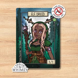 May include: A fantasy art card featuring an Elf Druid with a green hooded cloak, holding a staff. The card has the text "ELF DRUID" and "TOKEN CREATURE - ELF DRUID". The card is labeled "HAND-DRAWN ORIGINAL ART" and "1/1".