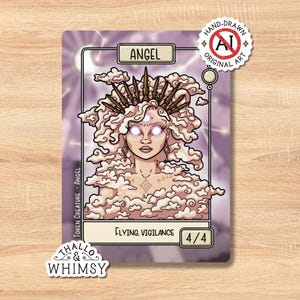 May include: A fantasy art card featuring an angel with cloud-like hair and a crown. The card has the text "ANGEL" at the top and "FLYING, VIGILANCE" at the bottom. The card is labeled "HAND-DRAWN ORIGINAL ART" and "TOKEN CREATURE - ANGEL".