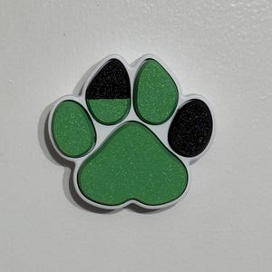 May include: A green and black paw print charm with a sparkly finish.